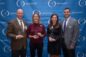 Group of four award recipients posing with trophies in front of an ApolloMD backdrop.