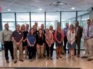 Group of healthcare professionals posing for a team photo inside an office building.