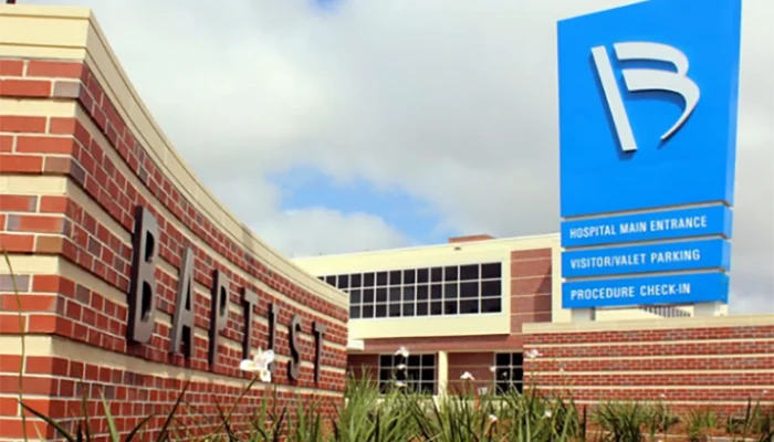 Exterior of a brick hospital building with a blue ApolloMD sign directing patients to the Main Entrance, Valet Parking, and Procedure Check-In.