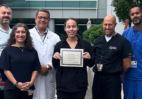 Photograph of five people accompanying a recent graduate who shows her diploma