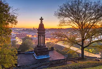 photograph of a monument on a viewpoint that shows a city at night