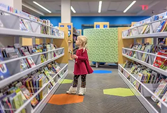 little blonde girl dressed in red looking at books