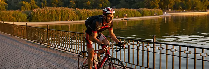 man riding a bicycle next to a lagoon