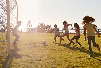 group of children playing soccer on the grass
