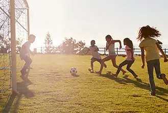 group of children playing soccer on the grass