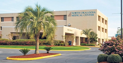 building next to a palm tree, with a sign that says okaloosa hospital