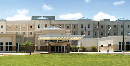 ivory colored building with grass in front of it and some flags