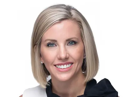 Headshot of Ashley Varner, smiling, wearing a white and black blouse.
