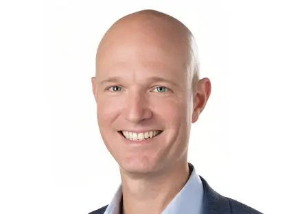 Headshot of Josh Hargraves smiling, wearing a black blazer and a white button-down shirt.