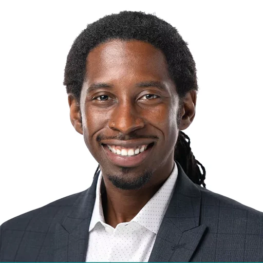 Headshot of Richard T. Benson, smiling, wearing a grey patterned blazer and a white button-down shirt.