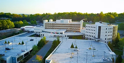An exterior photograph of the UNC Health Blue Ridge facility in Morganton, showing a modern brick and glass building with prominent 