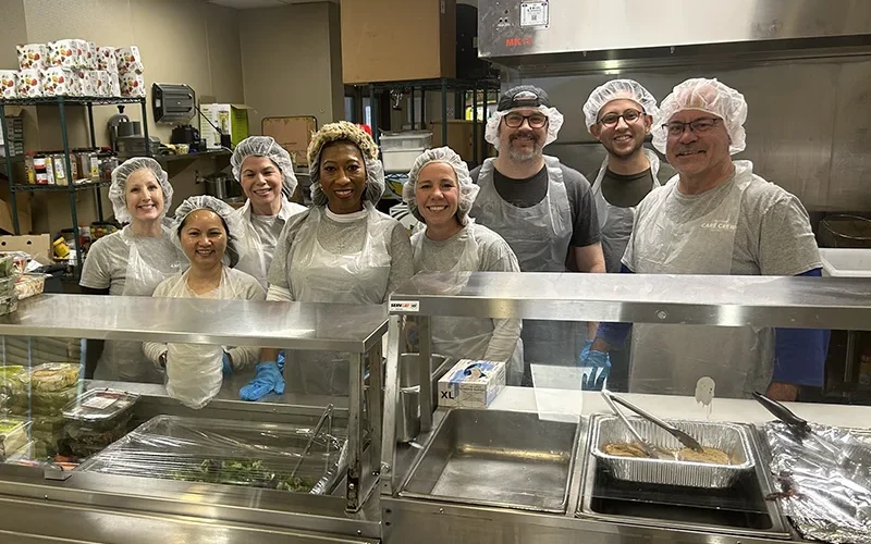A group of volunteers in blue 'ApolloMD' shirts working together at the Atlanta Community Food Bank to sort and pack food for those in need.