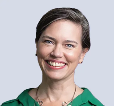 Professional headshot of a Strategic Advisory Board member. She is a smiling woman with short, grey-toned hair, wearing a vibrant green top and a silver necklace against a neutral grey background.