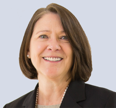 A smiling person with shoulder-length brown hair in a black blazer and pearl earrings, set against a plain light background, conveying a professional and approachable tone.