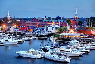 Scenic harbor view at dusk with numerous white yachts docked, colorful buildings in the background, and a serene, peaceful ambiance.