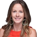 Closeup of a women, she has light brown hair, an orange top, and hoop earrings