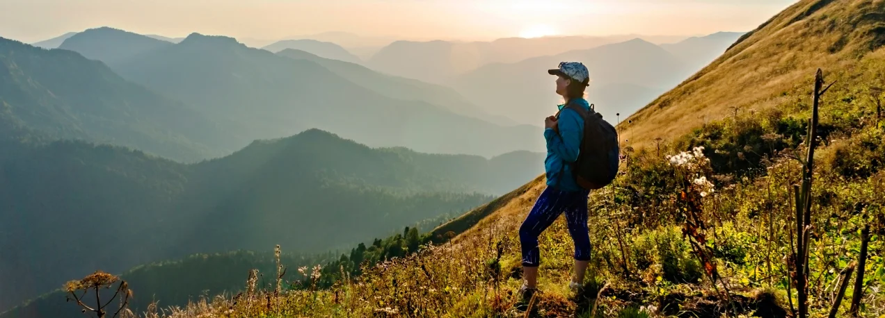 A woman hiking, she looks over a mountain range