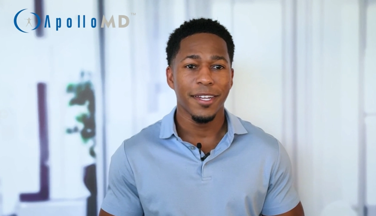 A person in a light blue shirt smiles, standing against a blurred interior background. The text 