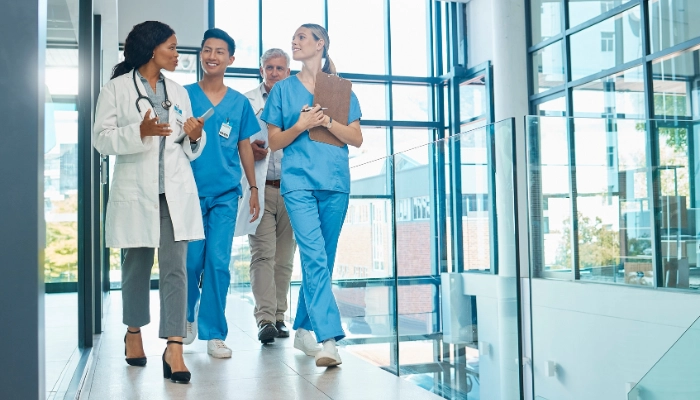 Four clinicians walking down a hospital hallway while discussing a case.