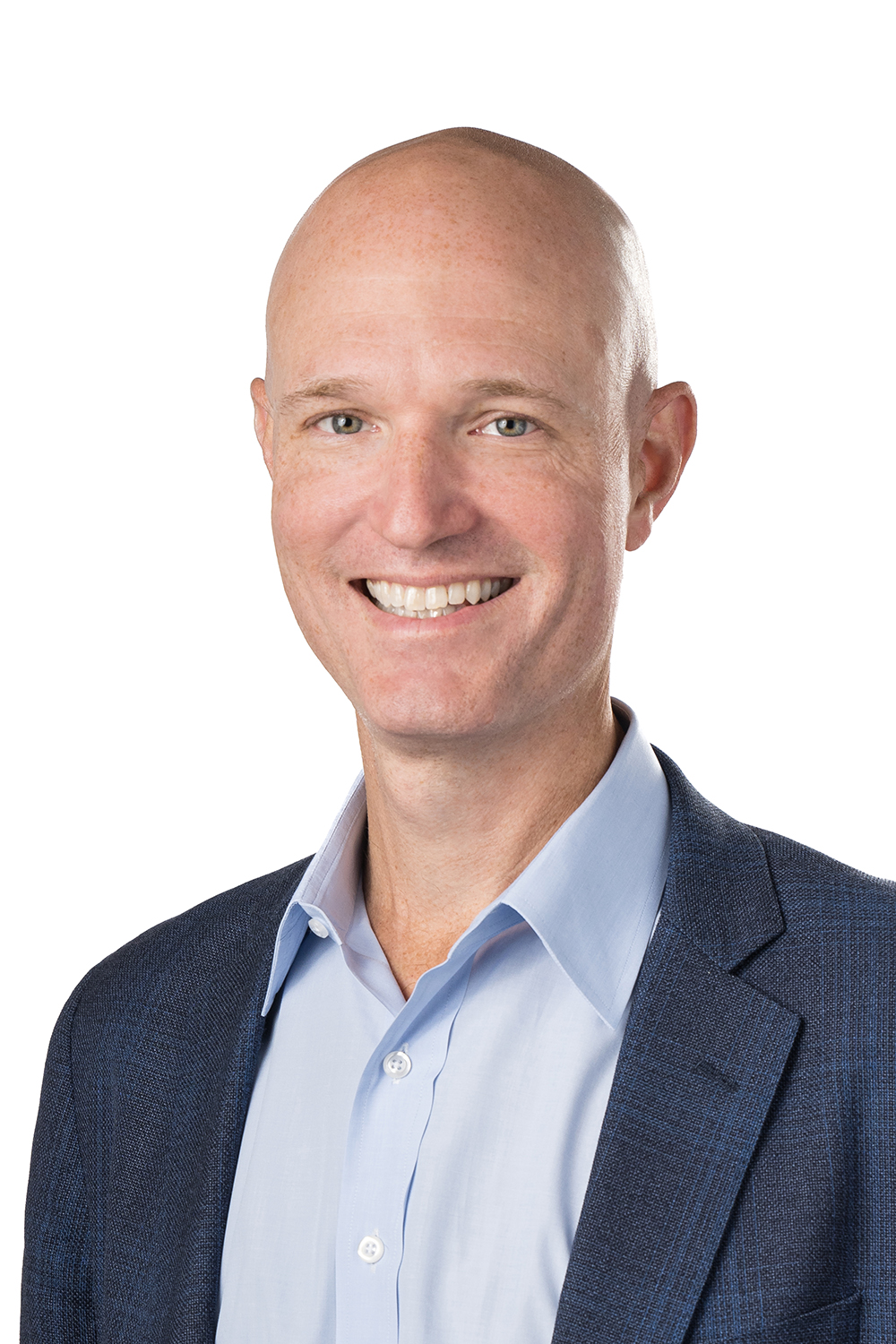 Professional headshot of a man wearing a blue button down shirt, and Navy blazer